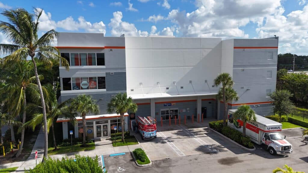 U-Haul self-storage facility exterior with white and red branding, palm trees, and rental trucks parked outside.