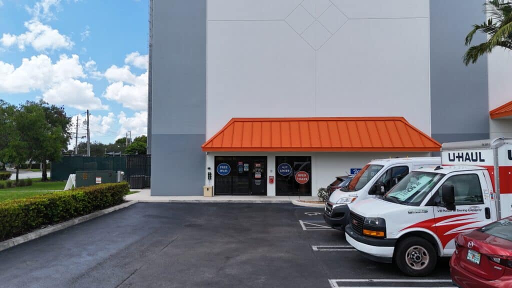 U-Haul rental trucks and vehicles parked outside self-storage facility with orange roof.