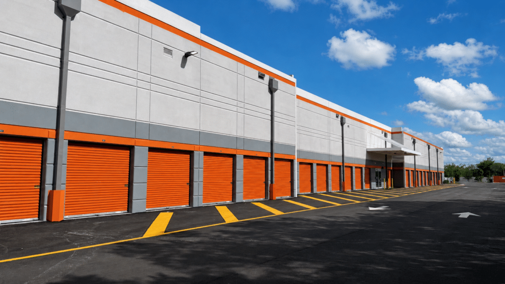 Exterior of modern self-storage facility with bright orange roll-up doors and gray paneling