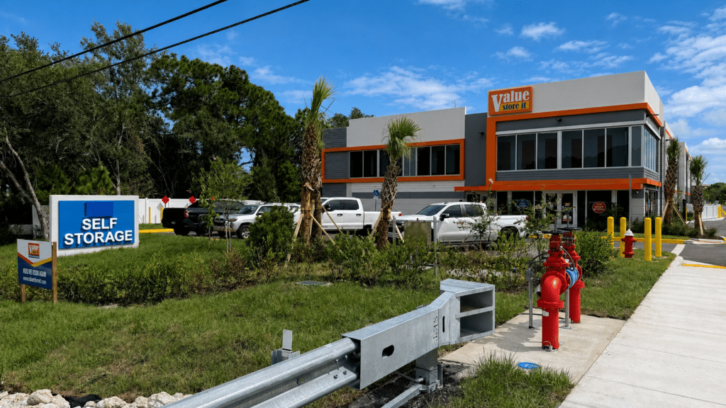 Value Store It self-storage facility exterior with orange and gray building, palm trees, and fire hydrants.
