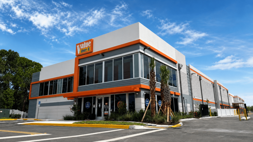 Value Store It self-storage facility exterior with orange and gray branding, ground-level drive-up access.